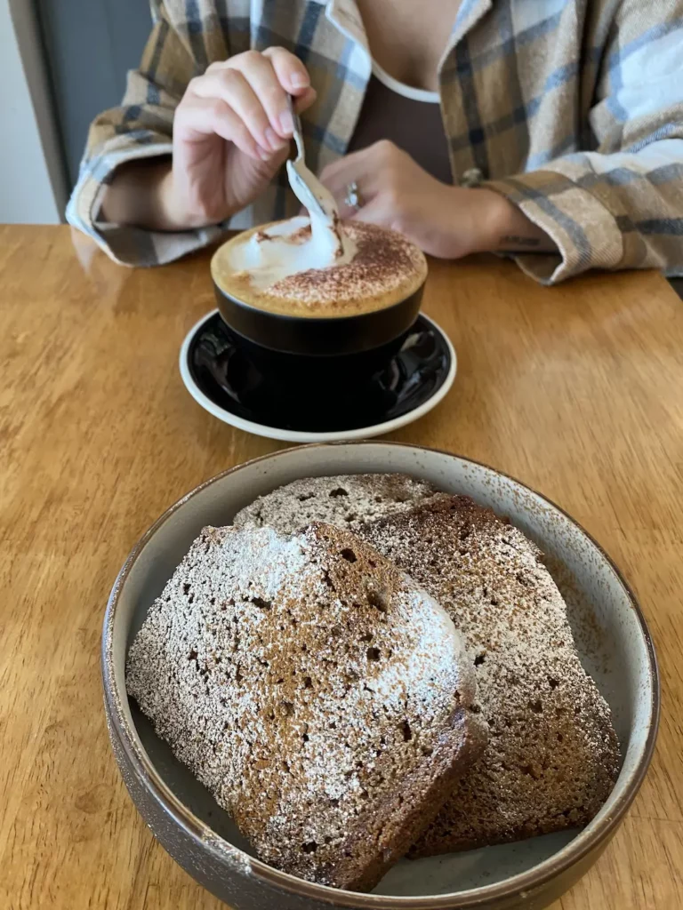 Banana bread in the foreground and cappuccino in the background at the winner of our ultimate Phuket breakfast guide: Poached Breakfast Cafe, Chalong, Phuket, Thailand