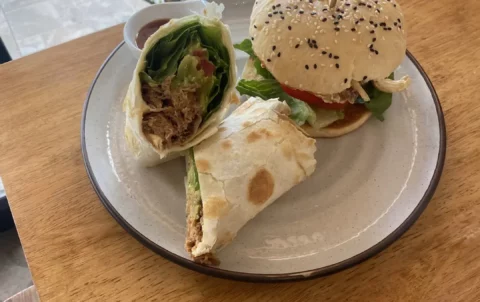 Pulled pork wrap and a curried chicken bagel on a plate next to a window at the spot with the best all day breakfast in Phuket: Poached Breakfast Cafe, Chalong, Phuket, Thailand