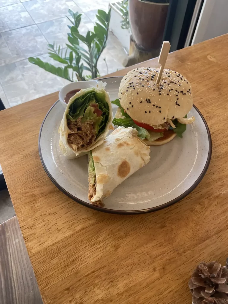 Pulled pork wrap and a curried chicken bagel on a plate next to a window at the spot with the best all day breakfast in Phuket: Poached Breakfast Cafe, Chalong, Phuket, Thailand