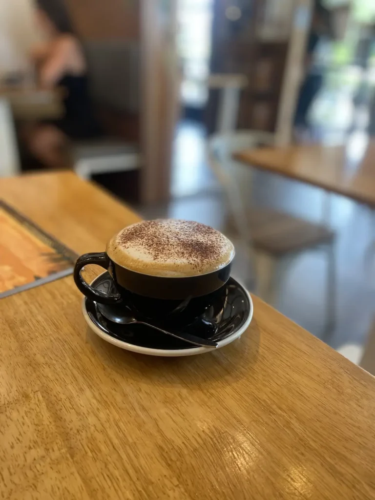 Cappuccino on a wooden table with a blurred background at one of the top food spots in Chalong: Poached Breakfast Cafe, Chalong, Phuket, Thailand
