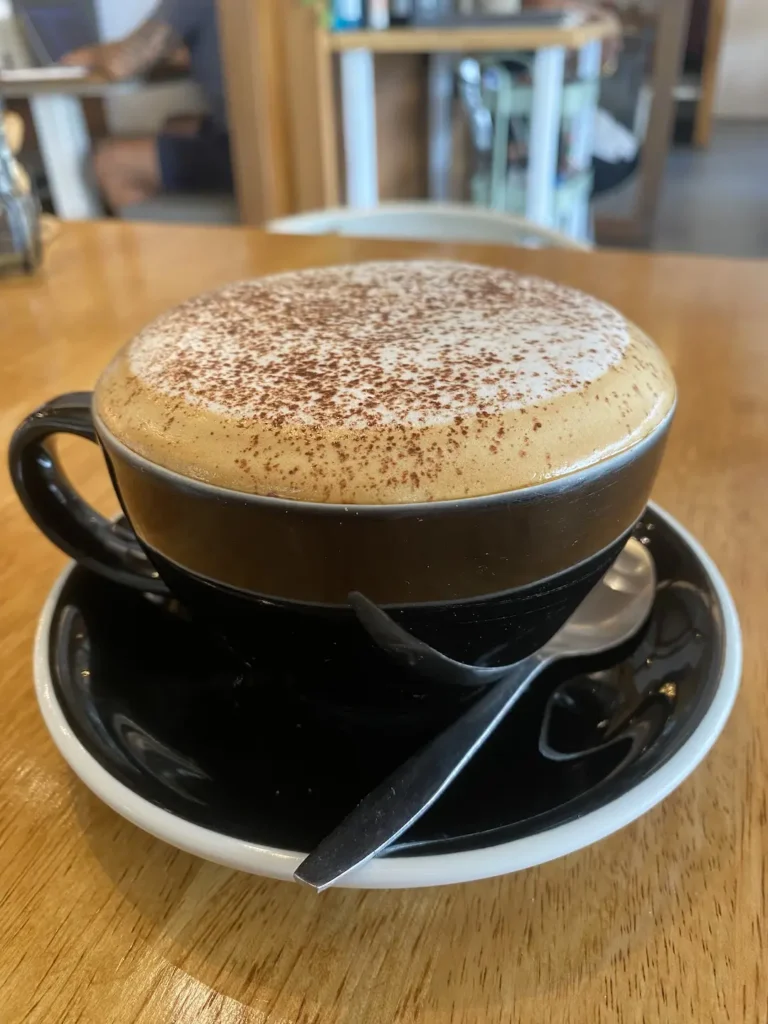 Frothy cappuccino with blurred background at the spot with the best coffee nearby Chalong: Poached Breakfast Cafe, Chalong, Phuket, Thailand