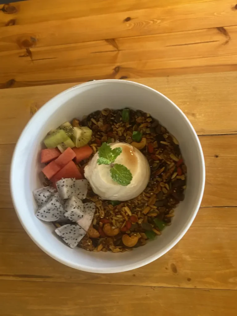 Breakfast Panna Cotta with a garnish on top, surrounded by museli, dragon fruit and watermelon. A delicious companion to a fresh salad in Chalong that can only be found at Poached Breakfast Cafe, Chalong, Phuket, Thailand