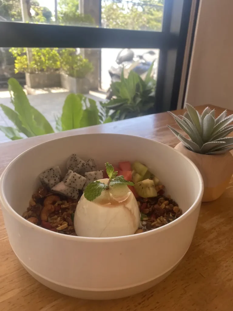 Vanilla panna cotta with fresh fruit and granola in a large bowl, next to a window. A great accompaniment to a hot chocolate in Chalong at Poached Breakfast Cafe, Chalong, Phuket, Thailand