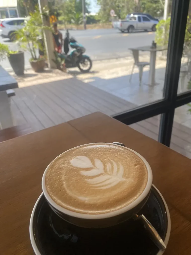 A delicious latte on a table next to a large window. A great alternative to a hot chocolate in Chalong at Poached Breakfast Cafe, Chalong, Phuket, Thailand