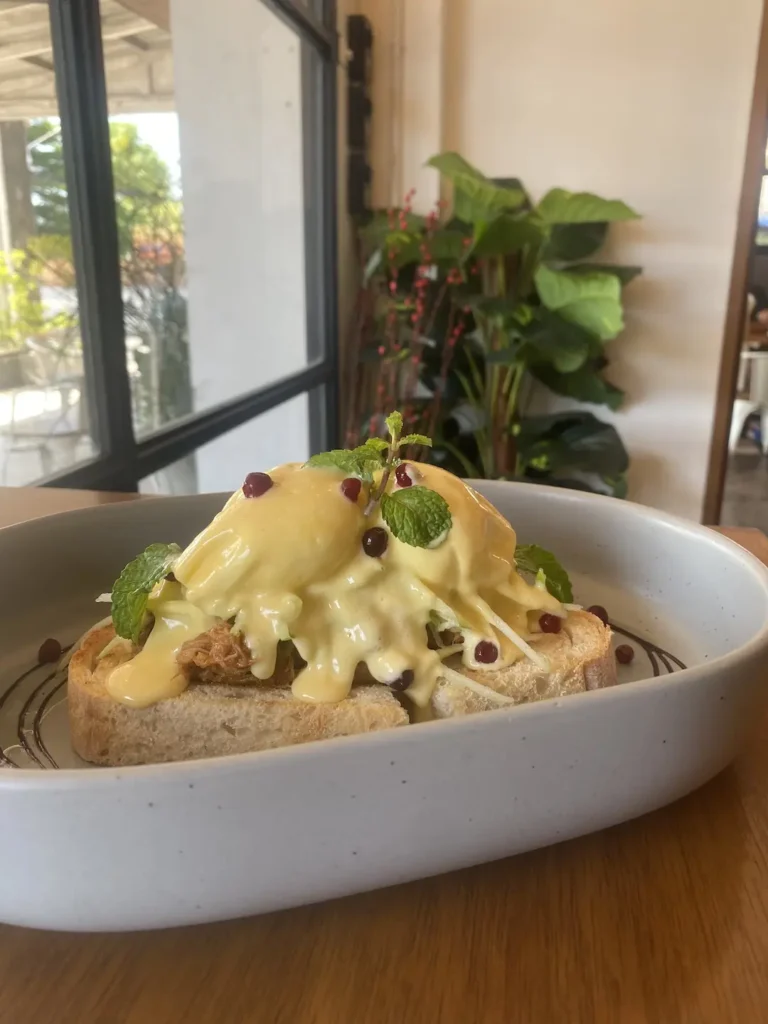 Our pulled pork eggs benedict with fresh mint and pomegranate in front of a window. A great alternative to the best bagel in Chalong, only found at Poached Breakfast Cafe, Chalong, Phuket, Thailand