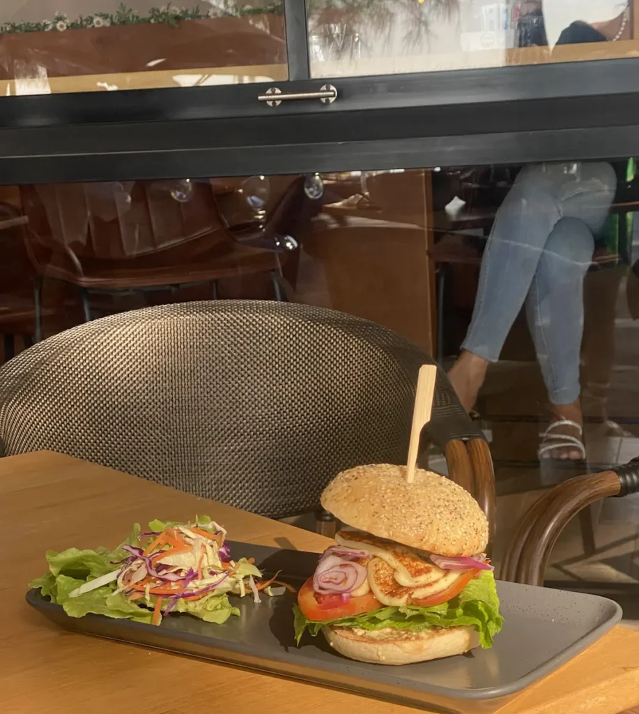 A delicious stacked burger in Chalong on a table in the sunshine with a side salad. Only at Poached Breakfast Cafe, Chalong, Phuket, Thailand