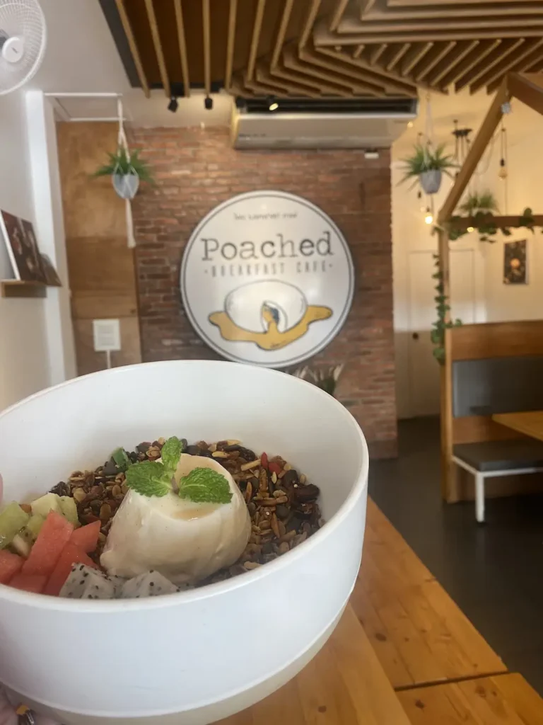 Delicious vanilla panna cotta with homemade granola and fresh fruit in front of our large instagram sign. Only at the spot with the best local coffee in Chalong at Poached Breakfast Cafe, Chalong, Phuket, Thailand