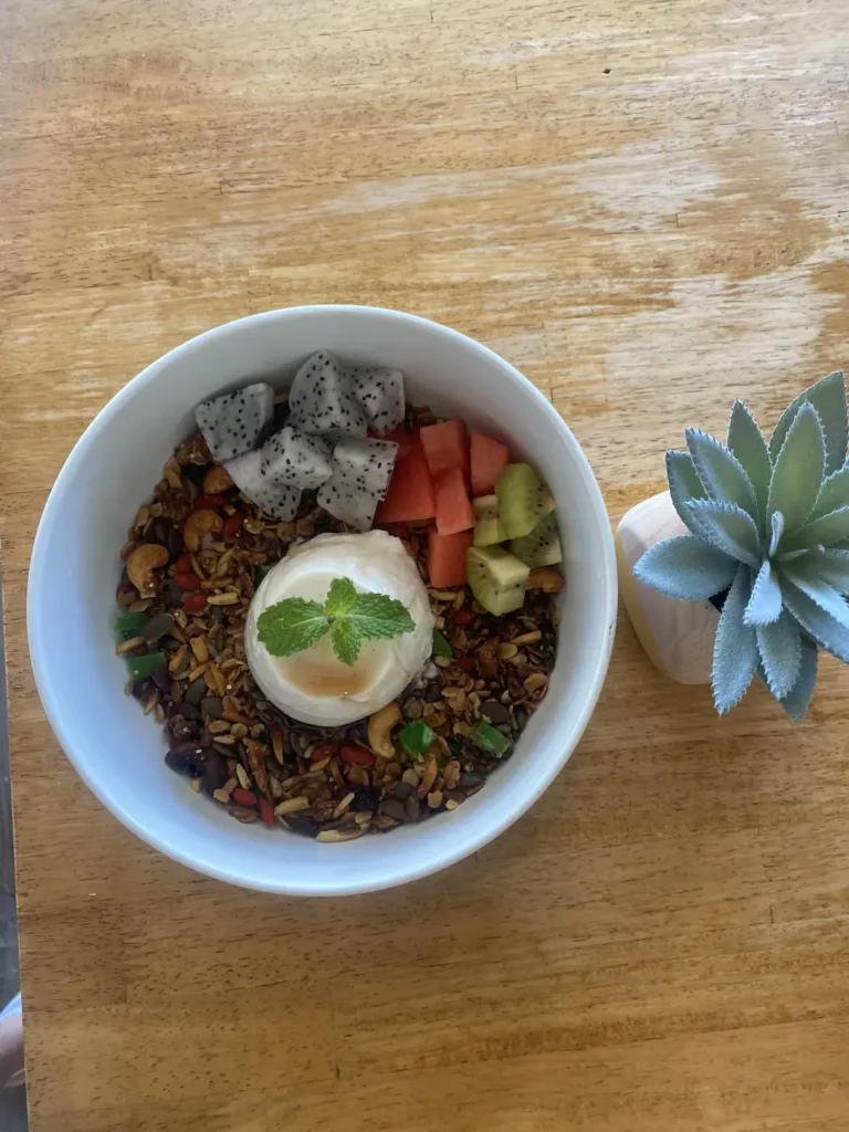 A round bowl filled with dragon fruit, watermelon, granola, nuts and a vanilla panna cotta in the centre, topped with a sprig of mint. This is the perfect meal to refuel before or after a fitness class in Chalong. Only at Poached Breakfast Cafe, Chalong, Phuket, Thailand