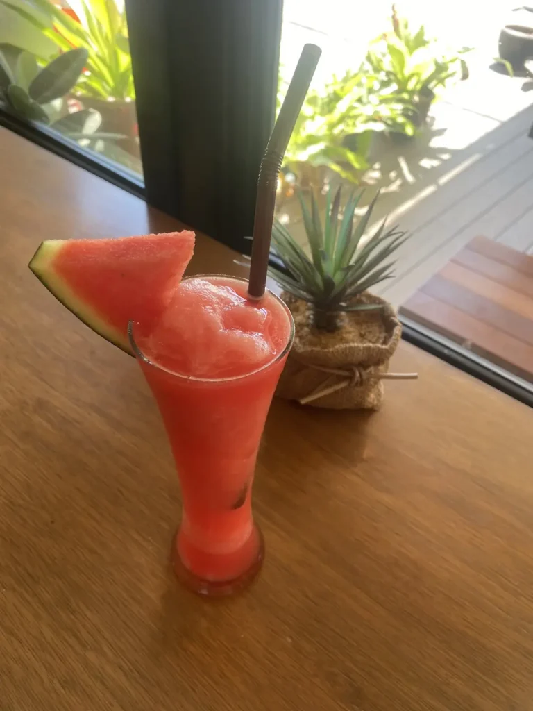 Watermelon smoothie in a tall glass with a watermelon wedge on the rim. Only at the spot with the best local coffee in Chalong at Poached Breakfast Cafe, Chalong, Phuket, Thailand