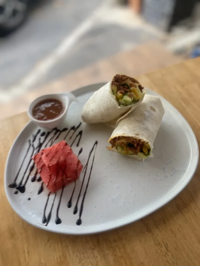 Spicy sausage wrap on a table with a dipping sauce and some watermelon at the number one place on the Phuket Travel Guide: Poached Breakfast Cafe, Chalong, Phuket, Thailand