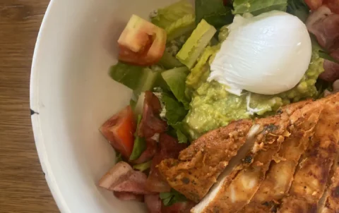 A close up photo of a bowl of chicken cobb salad with bacon, tomato, lettuce, a poached egg, blue cheese and smashed avocado at the best place to fuel up before a day of snorkelling in Phuket - Poached Breakfast Cafe, Chalong, Phuket, Thailand