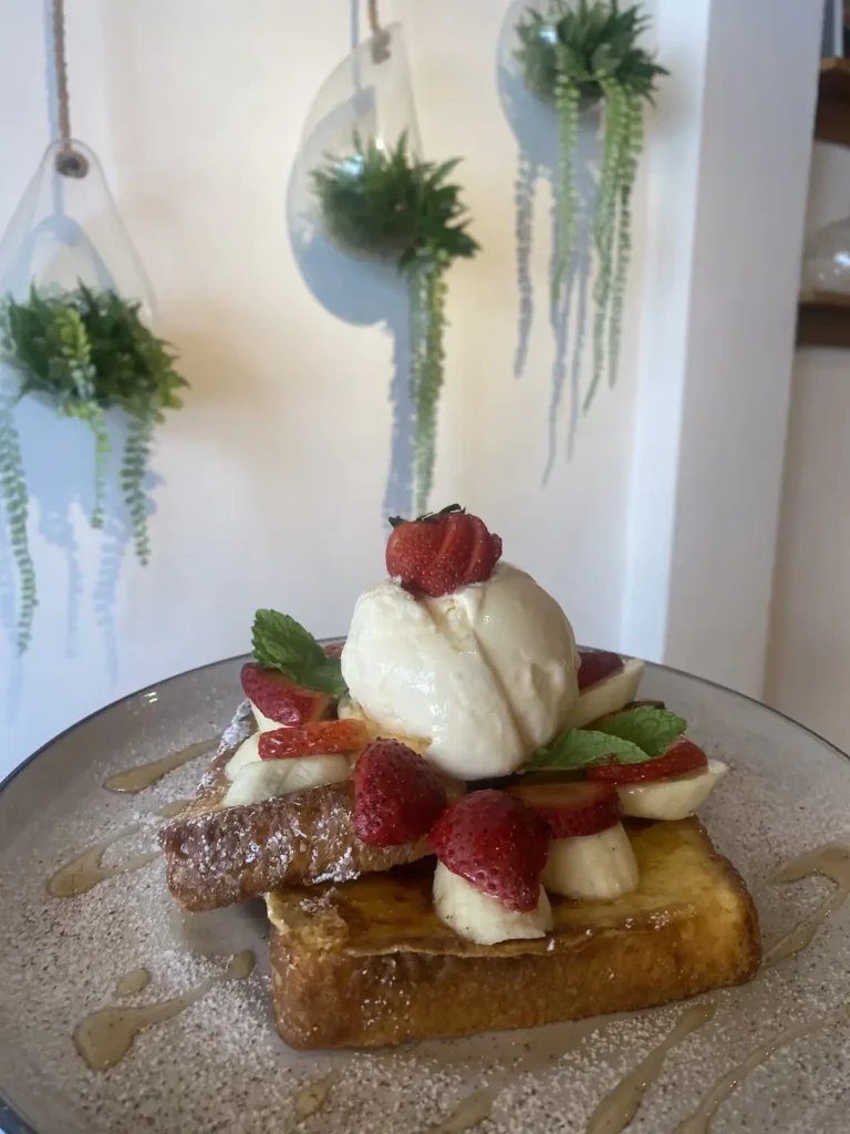 French toast with banana, strawberries and ice cream in front of some hanging terrariums at the best place to fuel up before a day at one of the waterparks in Phuket - Poached Breakfast Cafe, Chalong, Phuket, Thailand
