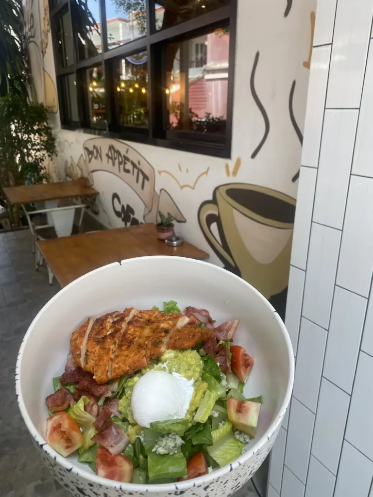 Bowl of Chicken cobb salad with bacon, avocado and a poached egg in front of some graffiti at the best place to fuel up before a day of snorkelling in Phuket - Poached Breakfast Cafe, Chalong, Phuket, Thailand